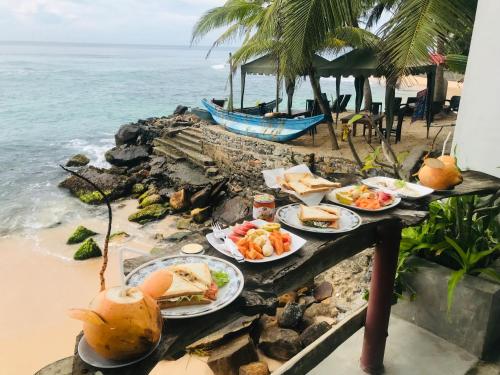 a table with plates of food on the beach at fantasea villa in Unawatuna