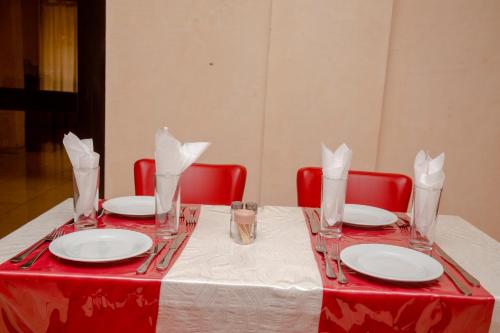 a red table with plates and glasses on top of it at Hôtel Millennium Kamissa in Bamako