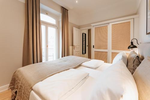 a bedroom with a large white bed with a window at Strandhotel Kurhaus Juist in Juist