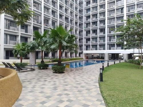 a large apartment building with a swimming pool and palm trees at Your home in the city in Manila