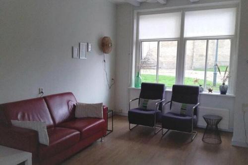 sala de estar con sofá rojo y 2 sillas en Beautiful house in the center of Harlingen, en Harlingen