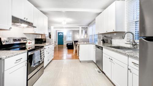 a large white kitchen with white cabinets and appliances at Homey Lodge - Cozy home / Walk to Revolution Mill / Near Downtown / Perfect for groups and family / Free parking in Greensboro