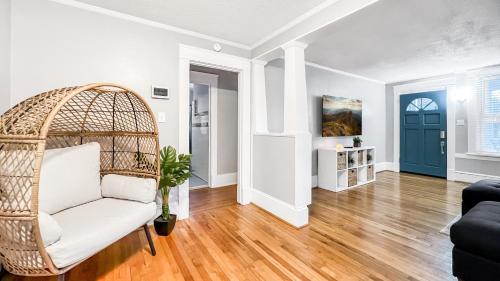 a living room with a rattan chair and a blue door at Homey Lodge - Cozy home / Walk to Revolution Mill / Near Downtown / Perfect for groups and family / Free parking in Greensboro