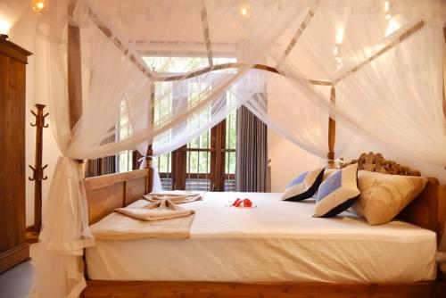 a bedroom with a canopy bed with white drapes at Villa Green Ice in Galle