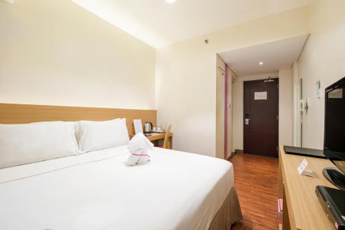 a hotel room with a white bed and a television at MySpace Hotel @BGC in Manila