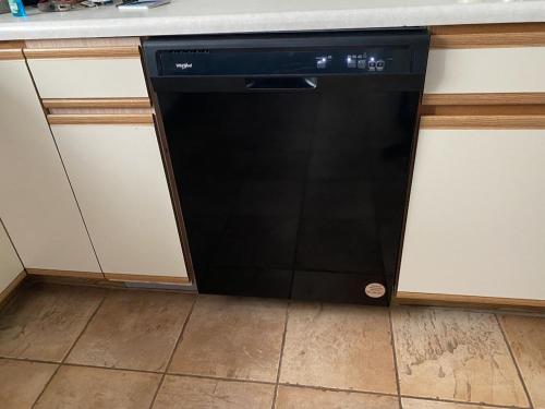 a black dishwasher sitting in the corner of a kitchen at Cozy Home in a Golf kart neighborhood and private pool in Palm Harbor