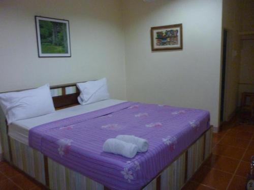 um quarto com uma cama roxa com toalhas em Baan Din Baramee Resort em Kamphaeng Phet