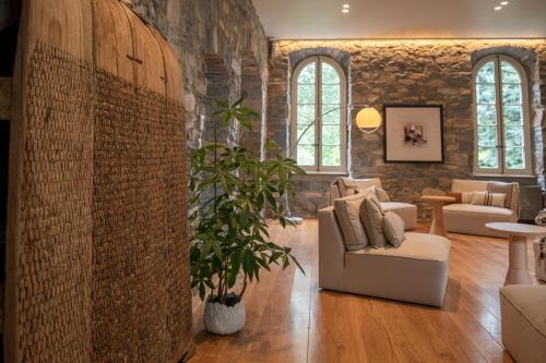 a living room with a stone wall and chairs and a plant at Couvent de la Salette & Spa in Millau