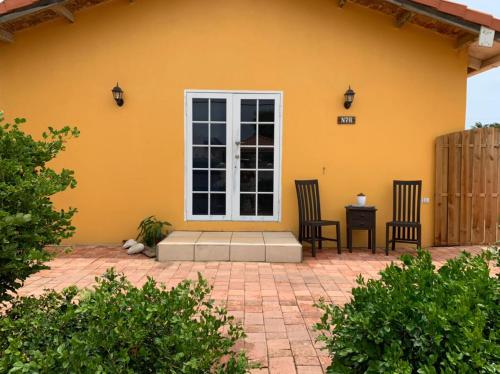 a yellow house with two chairs and a window at Local Home Aruba in Catiri