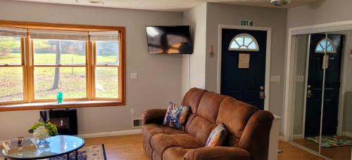 a living room with a brown couch and a glass table at Experience The Serenity Of Pineapple Acre Pocono in Stroudsburg
