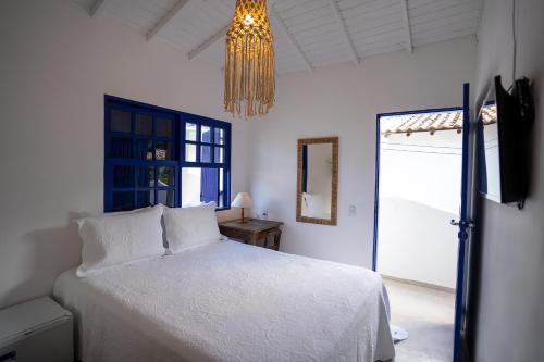a bedroom with a white bed and a chandelier at Arandu Casa Hotel Quadrado in Trancoso