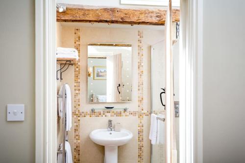a bathroom with a sink and a mirror at Clematis cottage in Cheltenham