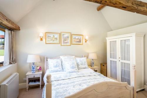 a bedroom with a bed and two lamps and a window at Clematis cottage in Cheltenham