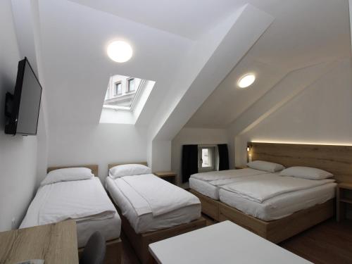 サラエボにあるVila Alexandraのベッド3台、テーブル、窓が備わる客室です。