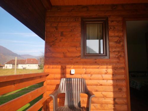 a bench sitting on the porch of a log cabin at Căsuțe Zăvoi Bulz in Bulz
