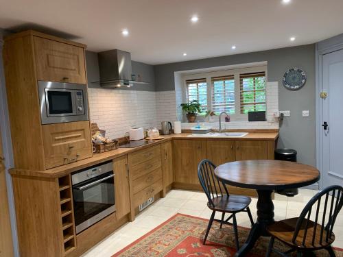 a kitchen with wooden cabinets and a table with chairs at Woodville Barn in Dunster
