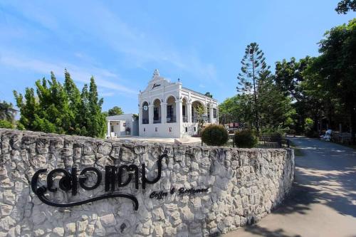 a stone wall in front of a white building at Je t'aime cafe & villa in Sing Buri