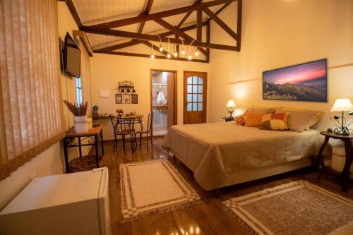 a bedroom with a large bed and a living room at Hospedaria Recanto da Val in Passa Quatro