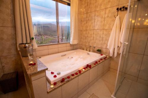 y baño con bañera y ventana. en Hospedaria Recanto da Val en Passa Quatro
