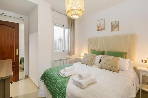 a bedroom with a large white bed with towels on it at Apartamento para vivir Granada con parking in Granada