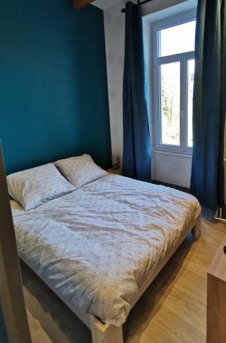 a bed in a room with a blue wall and a window at Studio 2 personnes in Le Mont-Dore