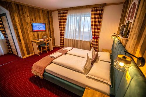 a hotel room with a large bed and a desk at KITZALPEN Pension in Hollersbach im Pinzgau