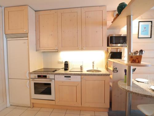 une cuisine avec des armoires en bois et un réfrigérateur blanc dans l'établissement Appartement confortable pour 6 avec balcon et parking aux Gets - FR-1-623-120, aux Gets