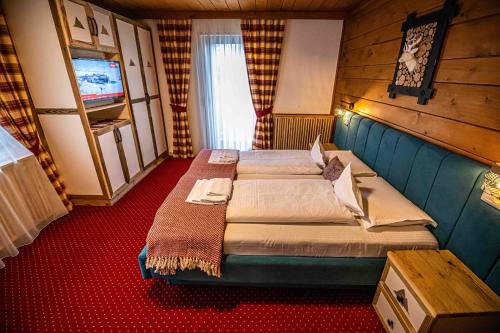 a bedroom with two beds and a television at KITZALPEN Pension in Hollersbach im Pinzgau