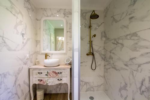 a white bathroom with a sink and a mirror at Gîte Spa & Nature in Saint-Chamassy