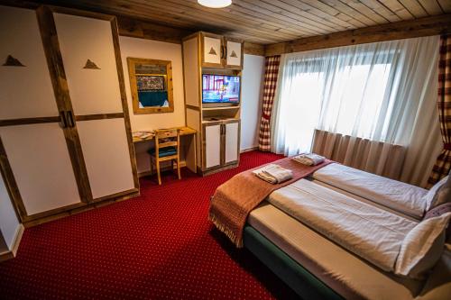 a hotel room with a bed and a television at KITZALPEN Pension in Hollersbach im Pinzgau