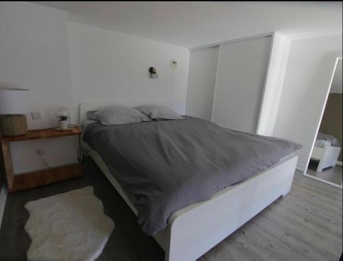 Ce lit se trouve dans une chambre dotée d'un mur blanc. dans l'établissement Une fenêtre sur l océan, Studio duplex dans résidence de standing avec piscine et vue sur mer, au Croisic