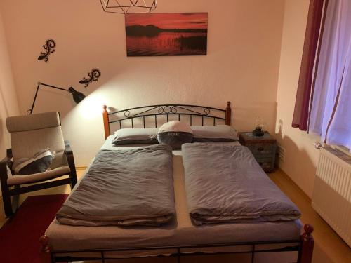 um quarto com uma cama e uma cadeira num quarto em Kathrin`s Appartment em Oelsnitz