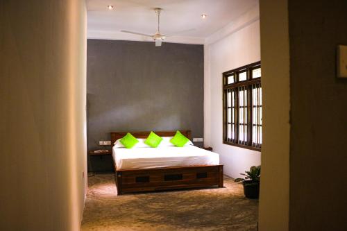 een slaapkamer met een bed met limoengroene kussens bij Cozy Resort in Matara