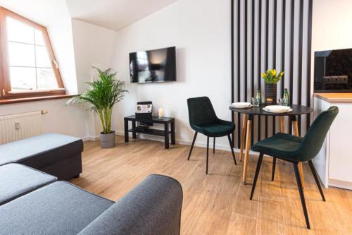 uma sala de estar com um sofá, uma mesa e cadeiras em Apartament Bianco Verde em Czestochowa