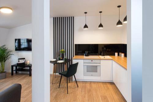 kuchnia z białymi szafkami, stołem i krzesłami w obiekcie Apartament Bianco Verde w mieście Częstochowa