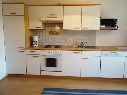 a kitchen with white cabinets and a sink at Pension Wald in Faistenau