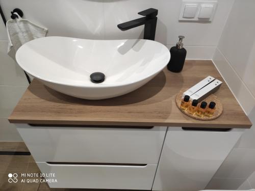 a bathroom with a white sink on a wooden counter at Apartament Pileckiego Nowy Dwór Mazowiecki Modlin Airport in Nowy Dwór Mazowiecki