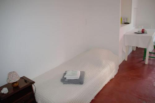 een wit bed in een kamer met een tafel bij Studio tout confort dans maison de caractère in La Bastide