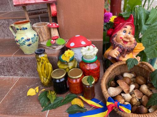 una cesta de comida y una figurita de una mujer junto a los tarros en Casa Grai Moroșănesc en Breb