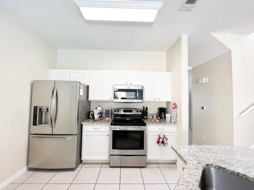 uma cozinha com armários brancos e electrodomésticos de aço inoxidável em Resort Home, Private Pool Orlando Disney sleeps12 em Kissimmee