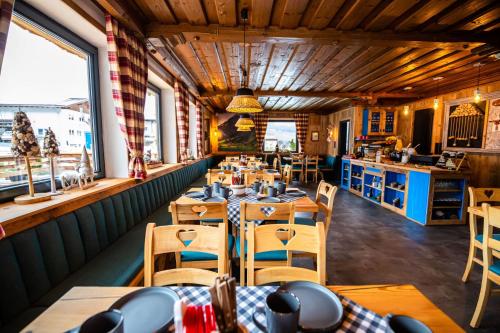 a restaurant with wooden tables and chairs and windows at KITZALPEN Pension in Hollersbach im Pinzgau