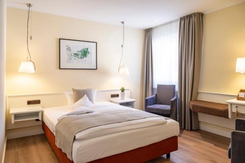 a hotel room with a bed and a chair at Hotel Deutscher Hof in Trier