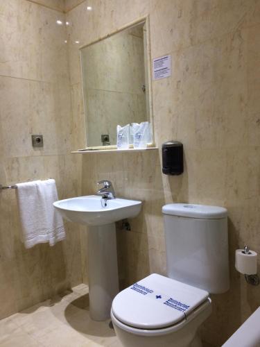 a bathroom with a toilet and a sink and a mirror at La Morona Hotel in Morón de la Frontera