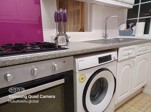 a kitchen with a stove and a washing machine at Poynters House - Huku Kwetu Luton & Dunstable - Spacious 2 Bedroom House-Private garden and parking in Luton