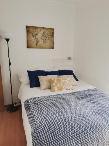 a bed with blue and white sheets and a picture on the wall at Studio acolhedor e confortável - Nazaré Waves in Nazaré