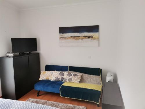 a bedroom with a blue couch and a tv at Studio acolhedor e confortável - Nazaré Waves in Nazaré