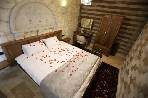 a bedroom with a bed with red rose petals on it at Castle Panorama House in Nevsehir