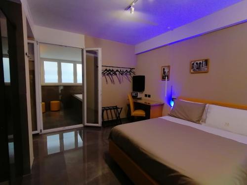 a bedroom with a bed and a desk with a purple light at Hotel XBusiness in Nola