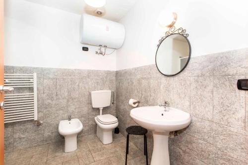 ein Badezimmer mit einem Waschbecken, einem WC und einem Spiegel in der Unterkunft Maison Sauze Centro in Sauze dʼOulx