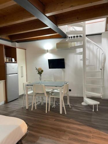 a dining room with a table and chairs and a spiral staircase at Easy Milano - Rooms and Apartments Navigli in Milan